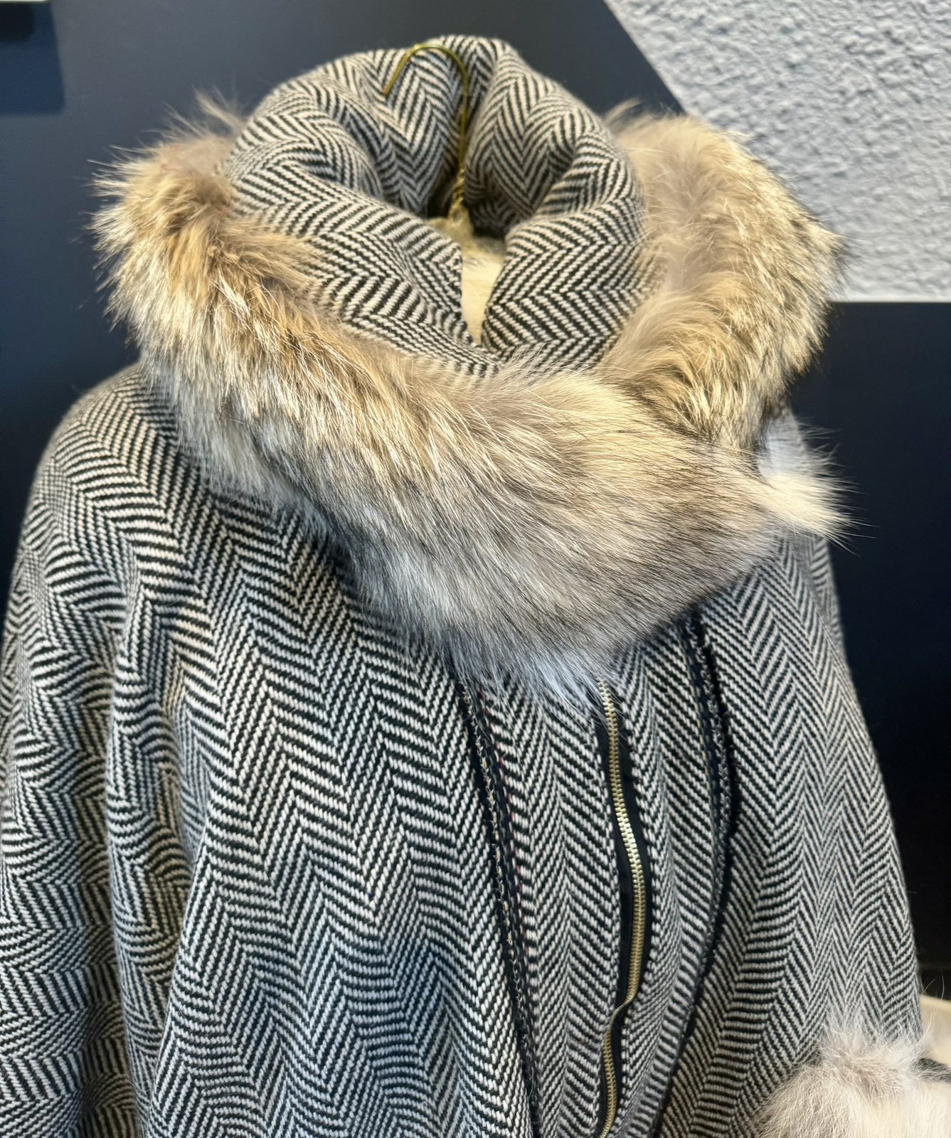 Coyote fur collar close-up on herringbone cape with brass zipper visible