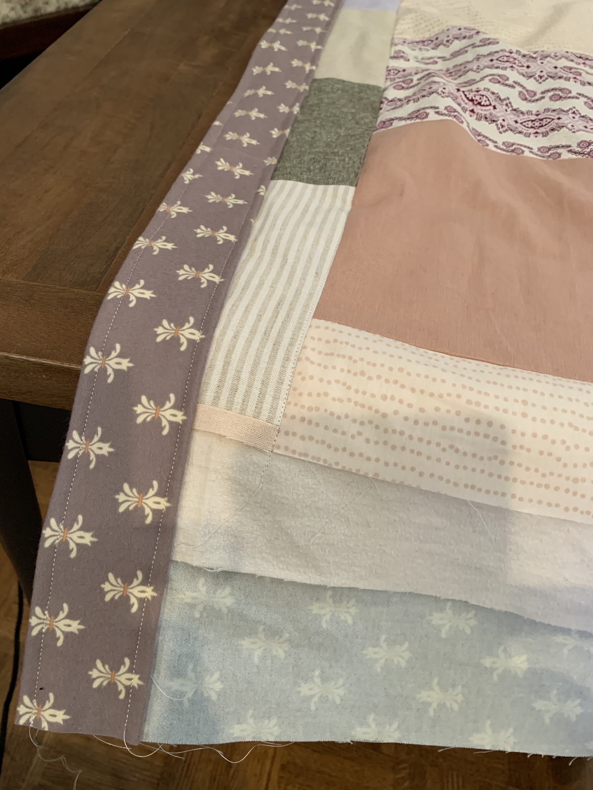 Detail of Dear Momma quilt edge — mauve fleur-de-lis border beside pink, striped, and dotted blocks