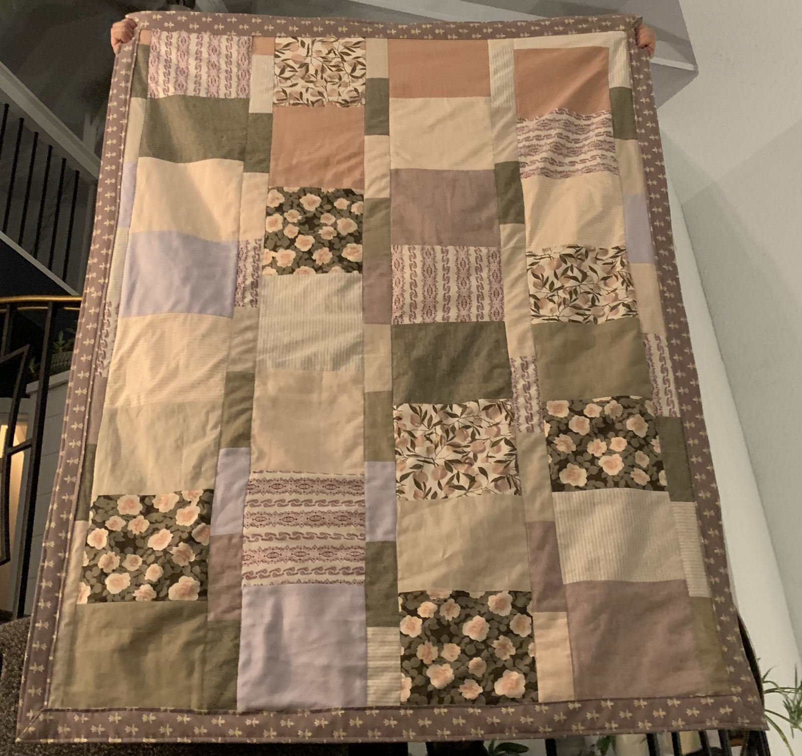 Dear Momma quilt held up full — patchwork of sage green, blush pink, lavender, cream, and floral prints with mauve border