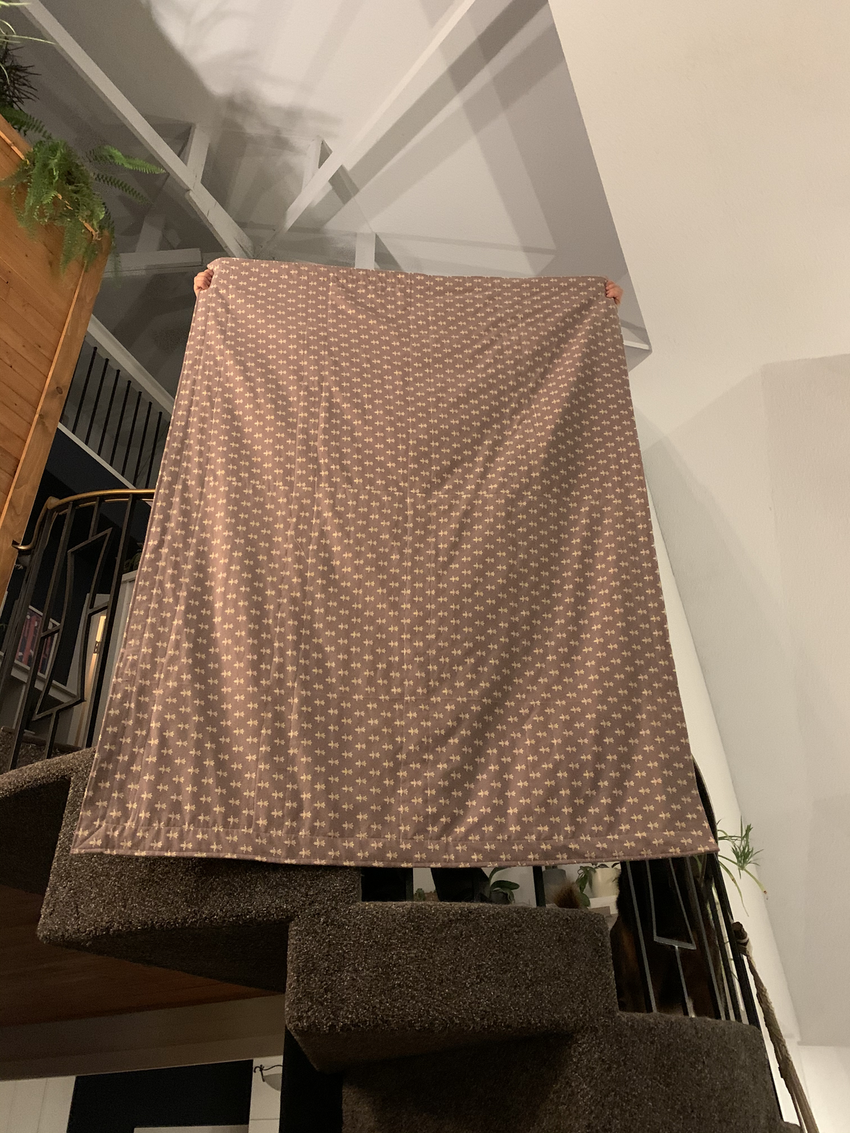 Dear Momma quilt backing — full mauve fleur-de-lis print held up over a stairwell
