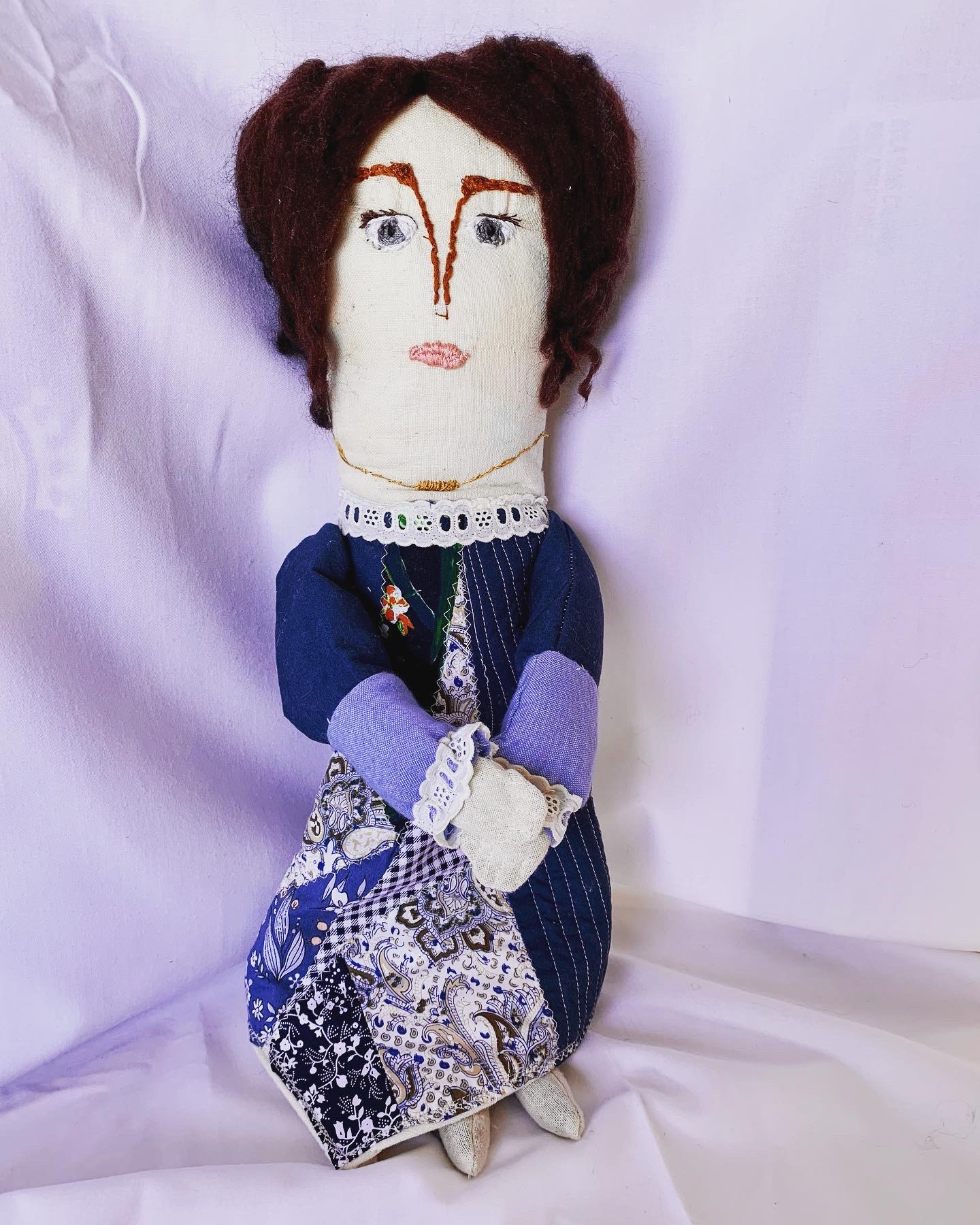 Charlotte — handmade genealogy doll with embroidered face, dark wool hair, navy pinstripe dress, lace collar and cuffs, patchwork blue apron