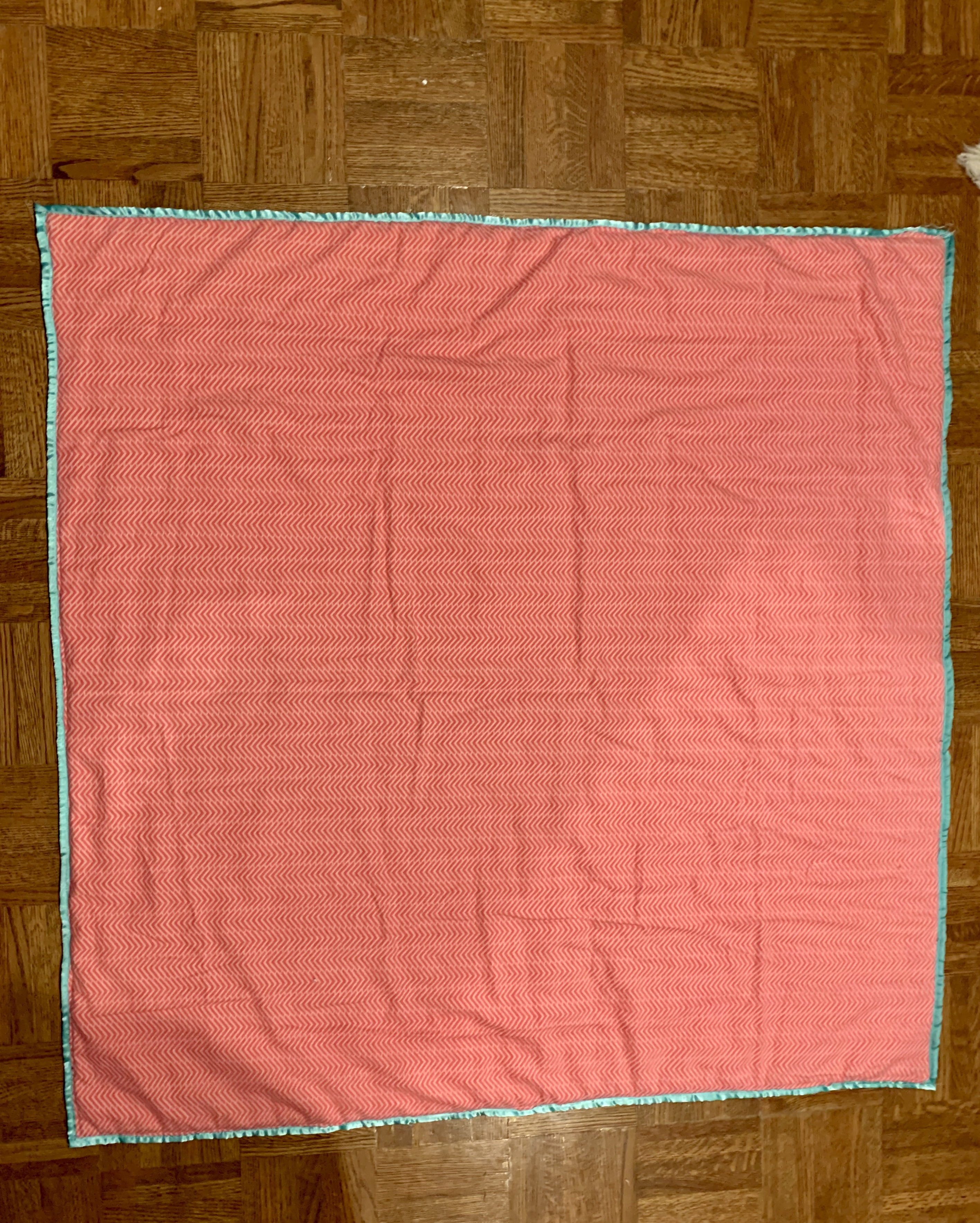 Little Fire quilt backing — solid coral chevron fabric with aqua satin binding