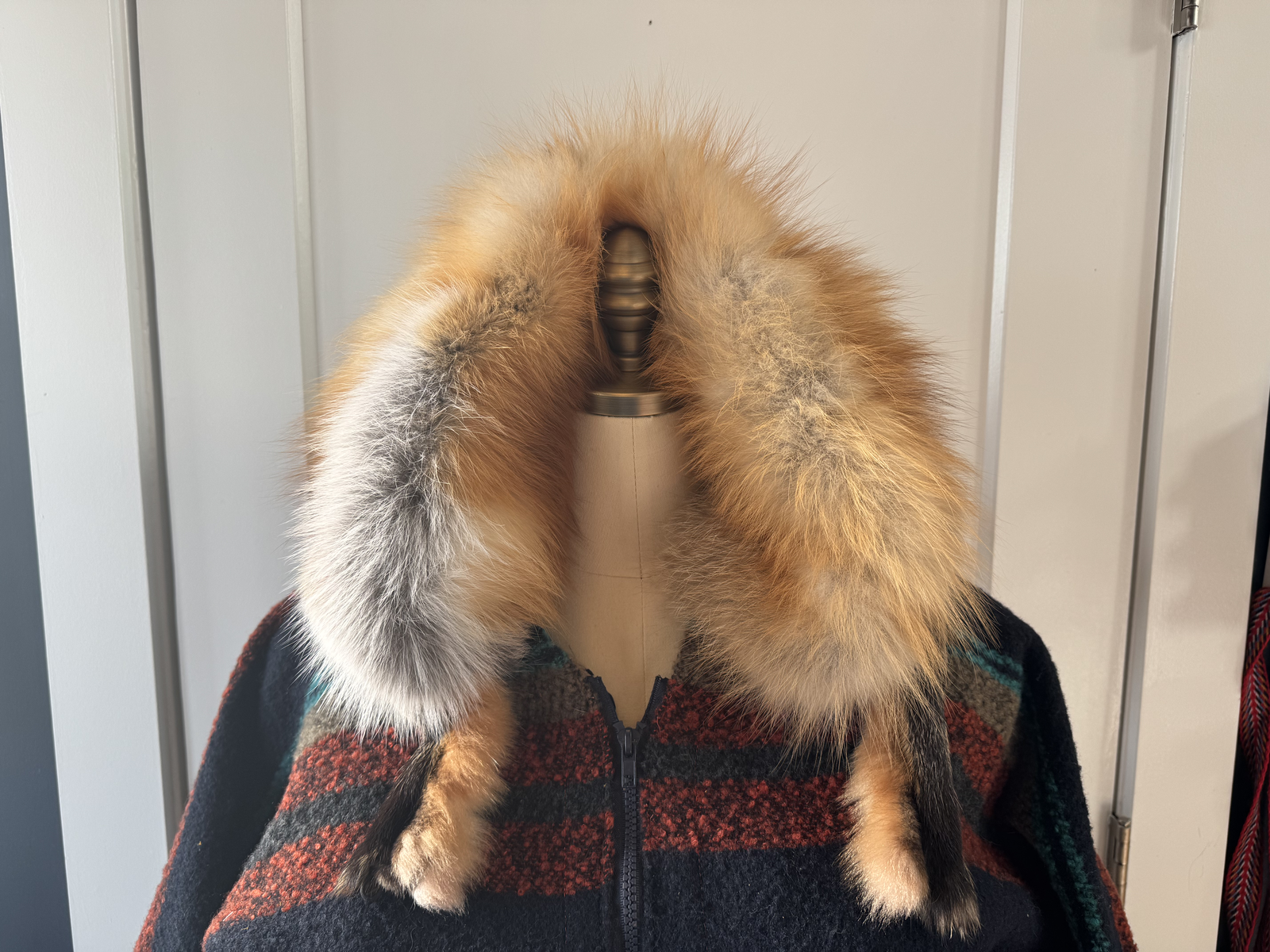 Fox fur collar detail on dress form — full golden fox fur framing the neckline over striped wool