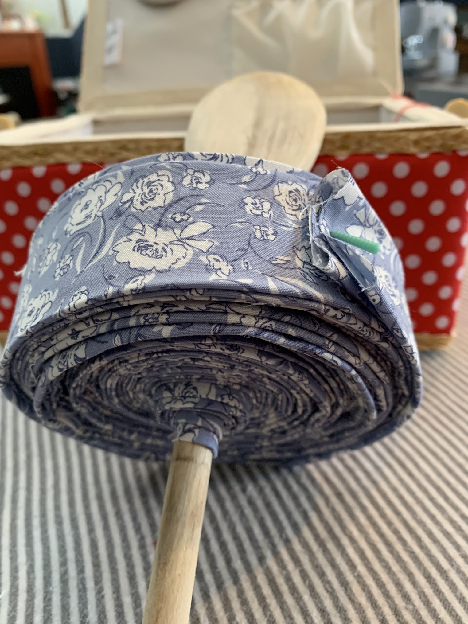 Custom quilt binding — blue floral fabric rolled on a dowel, ready to finish the quilt edge