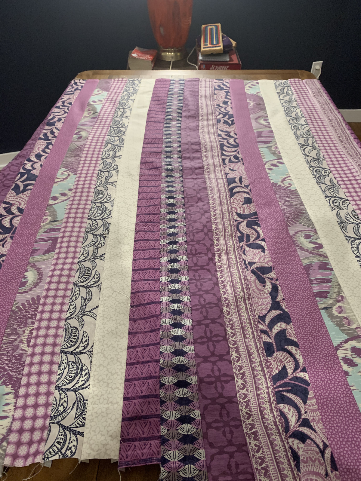 Purple Raining Prints strips laid out vertically on table — purple, navy, pink gingham, paisley, and cream prints