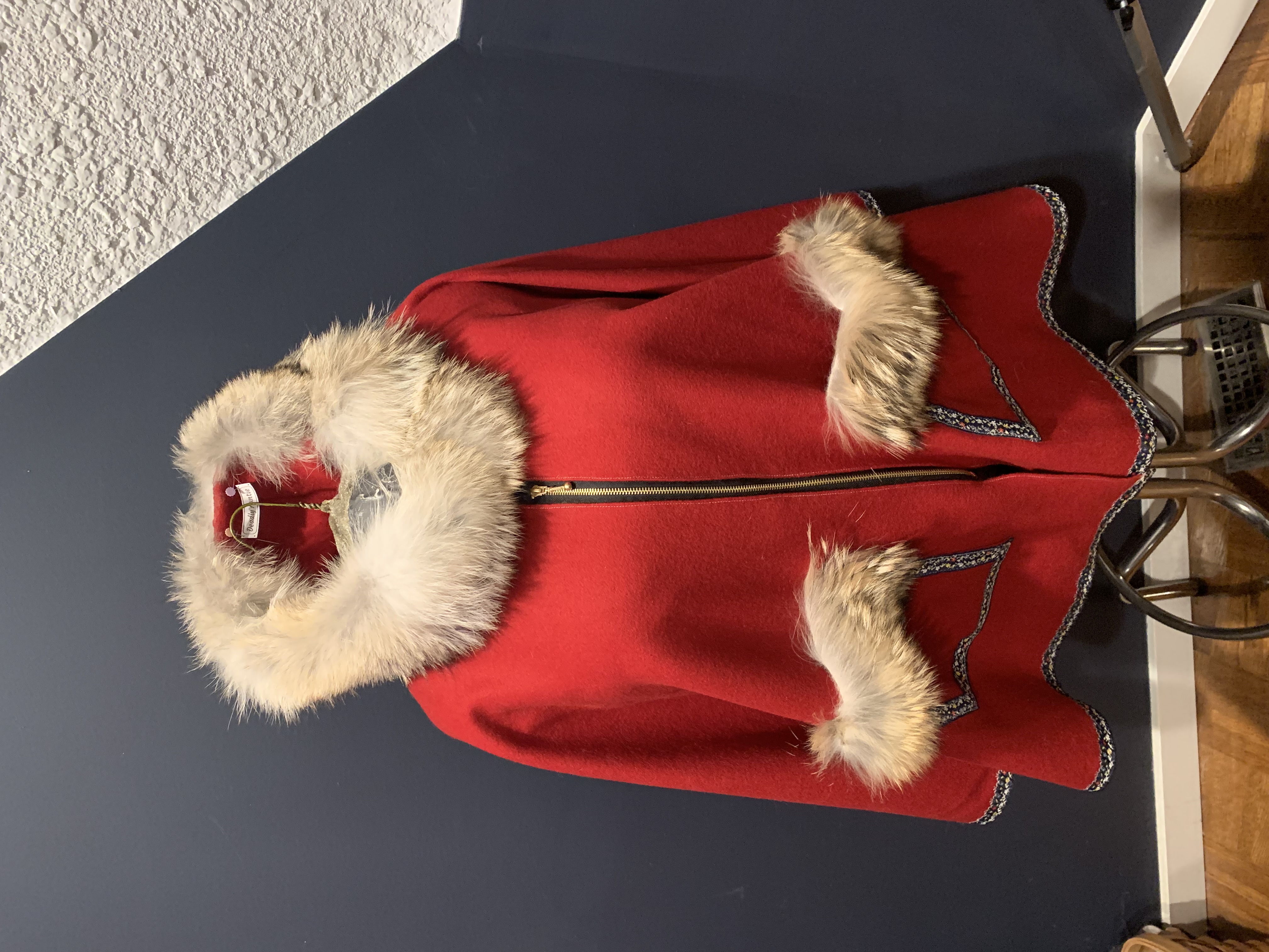 Red and Coyote cape on dress form — red wool with coyote fur hood and pocket trim, embroidered hem, brass zipper