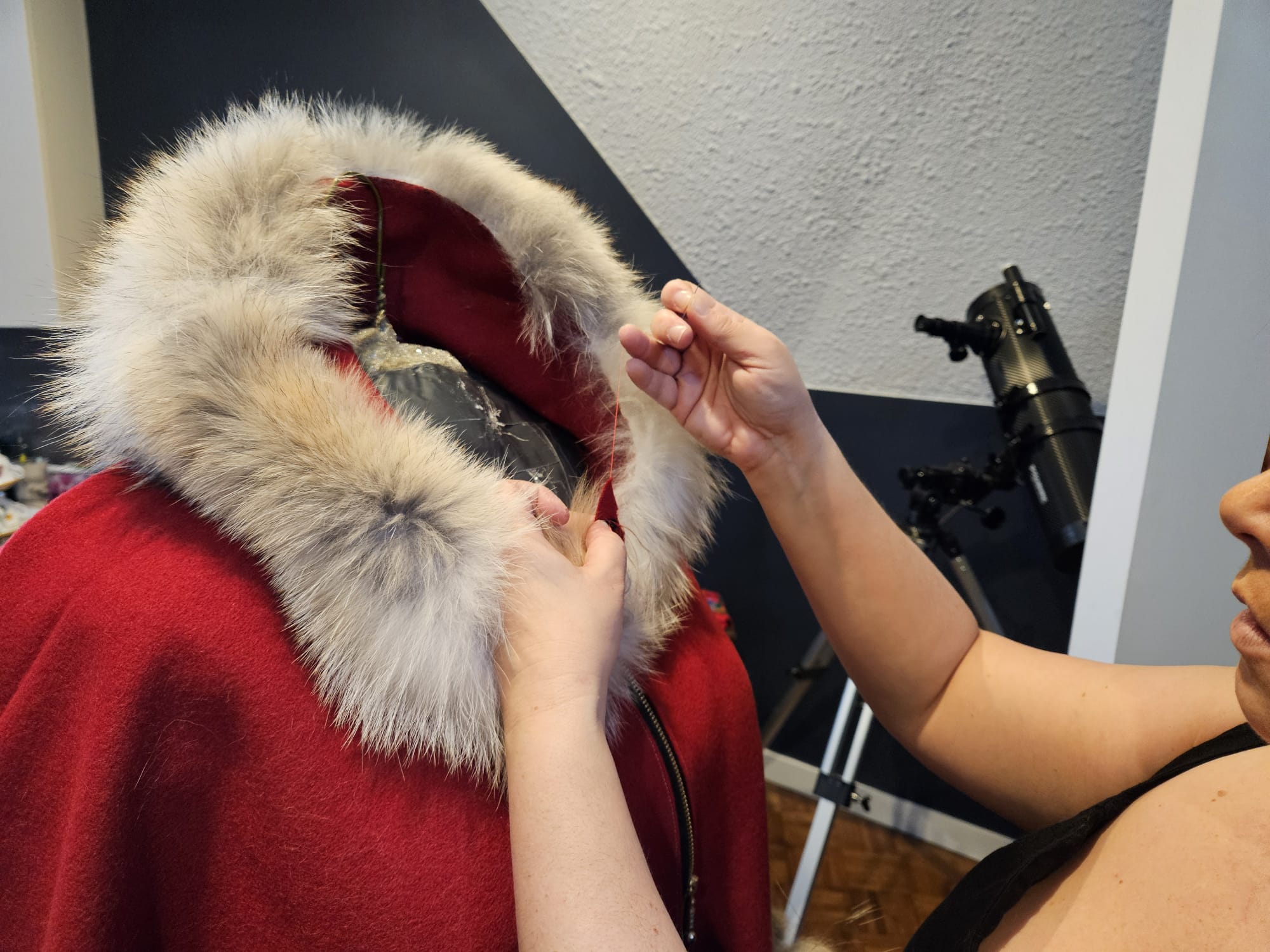 Close-up of the coyote fur hood on the Red and Coyote cape — hands adjusting the fur lining